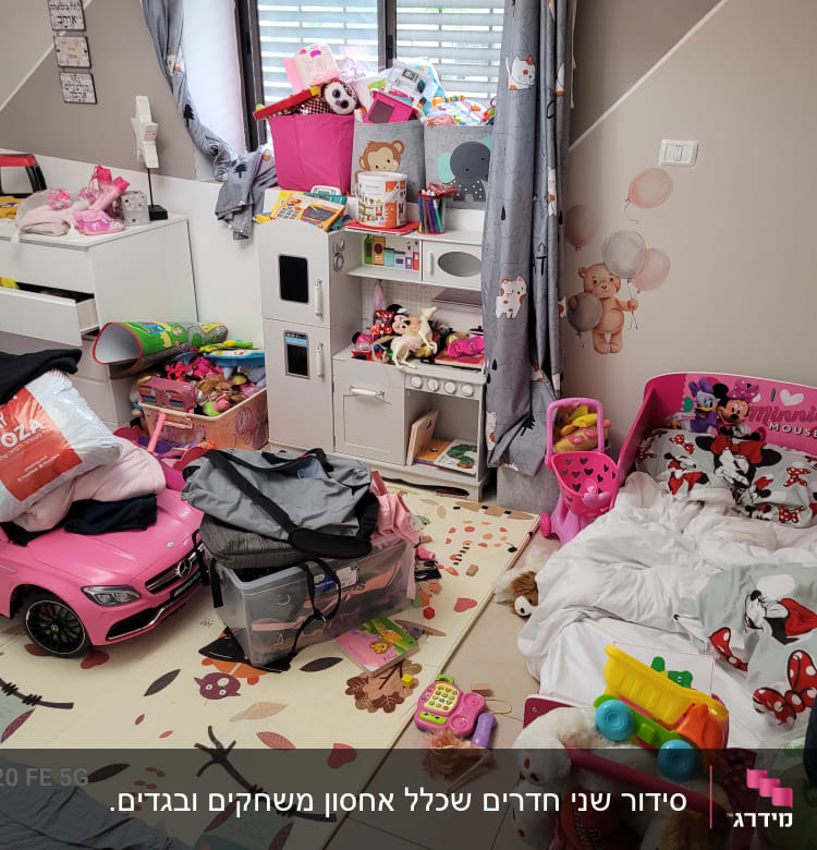 חדר ילדים מבולגן עם צעצועים ומיטה ורודה